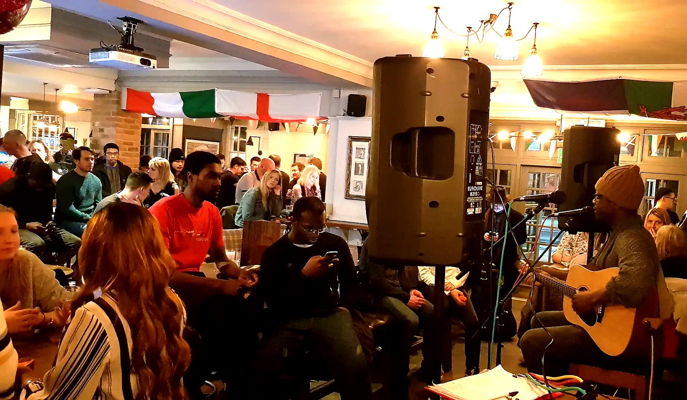 Packed pub crowd watching a live acoustic performer at a UK Pub Partner event
